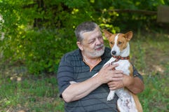 Senior man talking to his cute dog basenji taking it in the hands while resting in summer park Royalty Free Stock Image Senior man talking to his cute dog basenji taking it in the hands while resting in summer park Royalty Free Stock Image