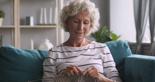 Senior mature woman knitting relaxing on sofa at home