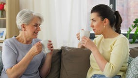 Senior mother and adult daughter drinking coffee