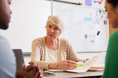 Senior teacher at desk talking to adult education students stock photos Senior teacher at desk talking to adult education students stock photos