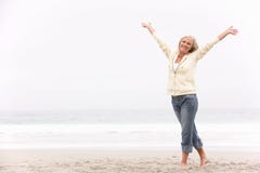 Senior Woman With Arms Outstretched On Beach