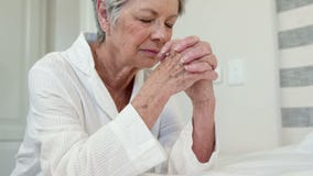 Senior woman praying on bed