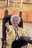 Senior woman sitting in her living room reading on a tablet royalty free stock image Senior woman sitting in her living room reading on a tablet royalty free stock image