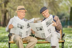 Seniors reading newspaper in a park stock images Seniors reading newspaper in a park stock images