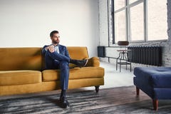 Sensación relajado El hombre de negocios joven hermoso y elegante está descansando sobre el sofá y está pensando en ideas del neg fotografía de archivo libre de regalías Sensación relajado El hombre de negocios joven hermoso y elegante está descansando sobre el sofá y está pensando en ideas del neg fotografía de archivo libre de regalías