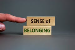 Sense of belonging symbol. Wooden blocks with words `sense of belonging` on beautiful grey background. Businessman hand. Busines