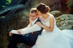 Sensitive portrait of the beautiful cheerful newlywed couple softly hugging on the rock. stock photography Sensitive portrait of the beautiful cheerful newlywed couple softly hugging on the rock. stock photography