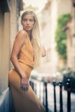 Sensual and attractive young blonde woman leaning against the wall on the street in the city.