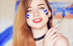 Sensuele vrouw met verf op het gezicht Meisje die een penseel met blauwe verf houden Gelukkige meisjesglimlach, stock foto Sensuele vrouw met verf op het gezicht Meisje die een penseel met blauwe verf houden Gelukkige meisjesglimlach, stock foto