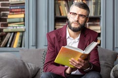 Sentiment barbu aux yeux noirs d'homme inspiré après lecture du livre intéressant photographie stock libre de droits Sentiment barbu aux yeux noirs d'homme inspiré après lecture du livre intéressant photographie stock libre de droits
