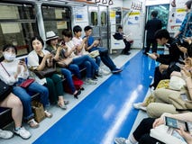 Seoul, Coreia do Sul - 12 de junho de 2017: Povos que sentam-se com telefones celulares no trem no metro de Seoul imagens de stock royalty free Seoul, Coreia do Sul - 12 de junho de 2017: Povos que sentam-se com telefones celulares no trem no metro de Seoul imagens de stock royalty free