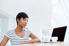 Serious attractive african businesswoman working with laptop and drinking coffee Royalty Free Stock Photos Serious attractive african businesswoman working with laptop and drinking coffee Royalty Free Stock Photos