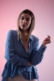 Serious young woman with hand and fingers in air in blue shirt looking at camera in studio isolated on pink royalty free stock images Serious young woman with hand and fingers in air in blue shirt looking at camera in studio isolated on pink royalty free stock images