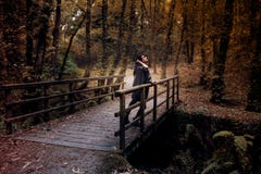 Serious young woman looking at the sky on a bridge in the middle of the forest in autumn stock images Serious young woman looking at the sky on a bridge in the middle of the forest in autumn stock images