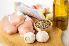 Serviette, huile v?g?tale, morceaux de blanc de poulet cru, ail, cuvette avec le condiment sur la planche ? d?couper sur la table image libre de droits Serviette, huile v?g?tale, morceaux de blanc de poulet cru, ail, cuvette avec le condiment sur la planche ? d?couper sur la table image libre de droits