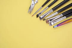 A set of different makeup artist brushes and scissors lie in a corner with copyspace for text on yellow color stock images A set of different makeup artist brushes and scissors lie in a corner with copyspace for text on yellow color stock images