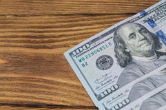 Several new bills of one hundred dollars lie on a wooden textured table diagonally. Visible part of the bills. stock photo Several new bills of one hundred dollars lie on a wooden textured table diagonally. Visible part of the bills. stock photo