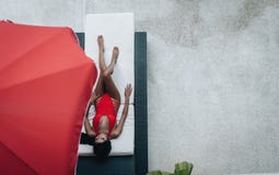 Sexig asiatisk kvinna i en r?d baddr?kt som l?gger, i sunbed p? poolsiden royaltyfri foto Sexig asiatisk kvinna i en r?d baddr?kt som l?gger, i sunbed p? poolsiden royaltyfri foto