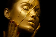 Sexy beauty woman with golden metallic skin. Gold paint smudges drips from the face and sexy lips