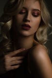 Sexy blonde girl with glowing skin and naked shoulders posing with contrast light stock image Sexy blonde girl with glowing skin and naked shoulders posing with contrast light stock image