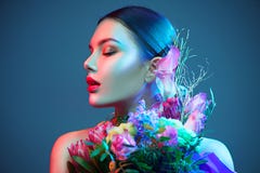 Sexy brunette model girl with bouquet of beautiful flowers. Beauty young woman with bunch of flowers in colorful neon lights