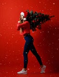 Christmas fitness sport woman wearing santa hat holding xmas tree on her shoulders. snowflakes stock photo Christmas fitness sport woman wearing santa hat holding xmas tree on her shoulders. snowflakes stock photo