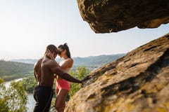 Sexy geschikt gemengd raspaar met perfecte organismen in sportkleding het stellen op het rotsachtige bergenlandschap stock afbeelding Sexy geschikt gemengd raspaar met perfecte organismen in sportkleding het stellen op het rotsachtige bergenlandschap stock afbeelding