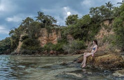 Sexy young beautiful girl in bikini sitting on the rocks at the tropical beach royalty free stock images Sexy young beautiful girl in bikini sitting on the rocks at the tropical beach royalty free stock images