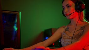 Sexy young woman sitting by the PC and playing games while sucking a lollipop