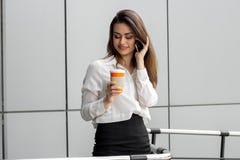 Señora atractiva joven del negocio que sostiene una taza de café y que habla en el teléfono Imagenes de archivo Señora atractiva joven del negocio que sostiene una taza de café y que habla en el teléfono Imagenes de archivo