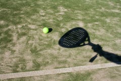 The shadow of a tennis racket on a green background.