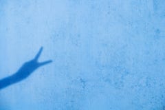 Shadow of two fingers up on blue wall background royalty free stock photography Shadow of two fingers up on blue wall background royalty free stock photography
