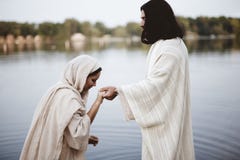 Shallow focus shot of a female wearing a biblical gown while holding the hand of Jesus Christ