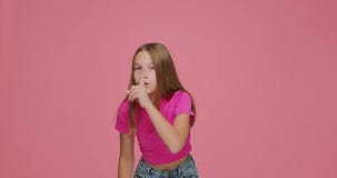 Shh silence gesture. Child girl hold finger on lips gesturing to be silent, to keep secret on pink background