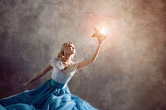 Shining star in hand, reach for the dream concept. Young woman holding a star in her hand