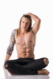 Shirtless härlig ung lång haired man och att sitta på golvet royaltyfri foto Shirtless härlig ung lång haired man och att sitta på golvet royaltyfri foto