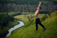 Shirtless sportieve jongelui past de mens die uitrekkende oefeningen buiten op landschapsachtergrond doen Horizontale mening royalty-vrije stock foto's Shirtless sportieve jongelui past de mens die uitrekkende oefeningen buiten op landschapsachtergrond doen Horizontale mening royalty-vrije stock foto's