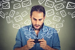 Shocked man busy sending messages emails from smart phone email icons flying of mobile phone