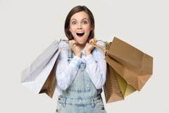 Shoppareflicka som rymmer högar av shoppingpåsar som isoleras på grå färger arkivfoton Shoppareflicka som rymmer högar av shoppingpåsar som isoleras på grå färger arkivfoton