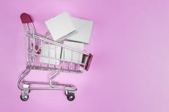 Shopping cart with boxes on pink background. The concept of delivering and online shop royalty free stock photos Shopping cart with boxes on pink background. The concept of delivering and online shop royalty free stock photos