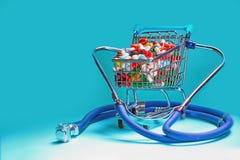 Shopping cart filled with pills with a stethoscope. Blue background. stock image Shopping cart filled with pills with a stethoscope. Blue background. stock image