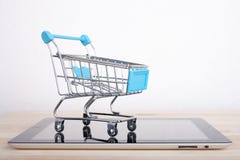 Shopping Cart over a Tablet PC on wooden table stock image Shopping Cart over a Tablet PC on wooden table stock image