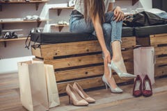 Shopping time!Trying on shoes by young woman sitting on bench at shop background stock photography Shopping time!Trying on shoes by young woman sitting on bench at shop background stock photography