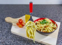 Sich hin- und herbewegende Gabel der Nudel im Knoblauch und im Öl, diente in einer Schüssel mit Speck und Tomaten lizenzfreie stockbilder Sich hin- und herbewegende Gabel der Nudel im Knoblauch und im Öl, diente in einer Schüssel mit Speck und Tomaten lizenzfreie stockbilder