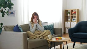 Sick woman blowing nose in paper tissue at home