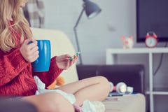 Sick young girl with pills and cup of tea sitting on the sofa. royalty free stock photography Sick young girl with pills and cup of tea sitting on the sofa. royalty free stock photography