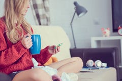 Sick young girl with pills and cup of tea sitting on the sofa. stock photography Sick young girl with pills and cup of tea sitting on the sofa. stock photography