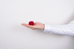 Side profile closeup cropped photo of hand holding closed red heart shaped small little box with ring inside isolated grey stock images Side profile closeup cropped photo of hand holding closed red heart shaped small little box with ring inside isolated grey stock images