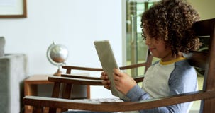 Side view of African american boy playing game on digital tablet on chair in lobby at hospital 4k stock footage Side view of African american boy playing game on digital tablet on chair in lobby at hospital 4k stock footage