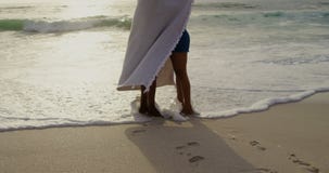 Side view of African American couple wrapped in blanket on the beach 4k stock video footage Side view of African American couple wrapped in blanket on the beach 4k stock video footage